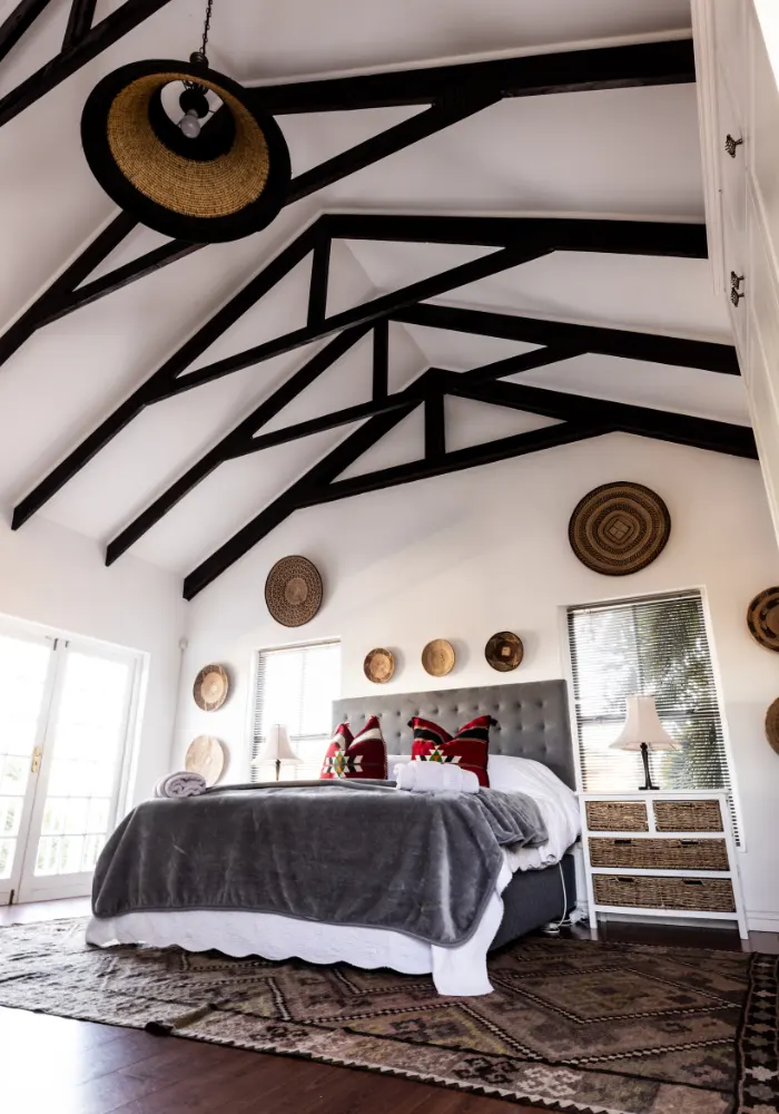 A beautiful bedroom in a new barndominium with vaulted ceilings and arched beams