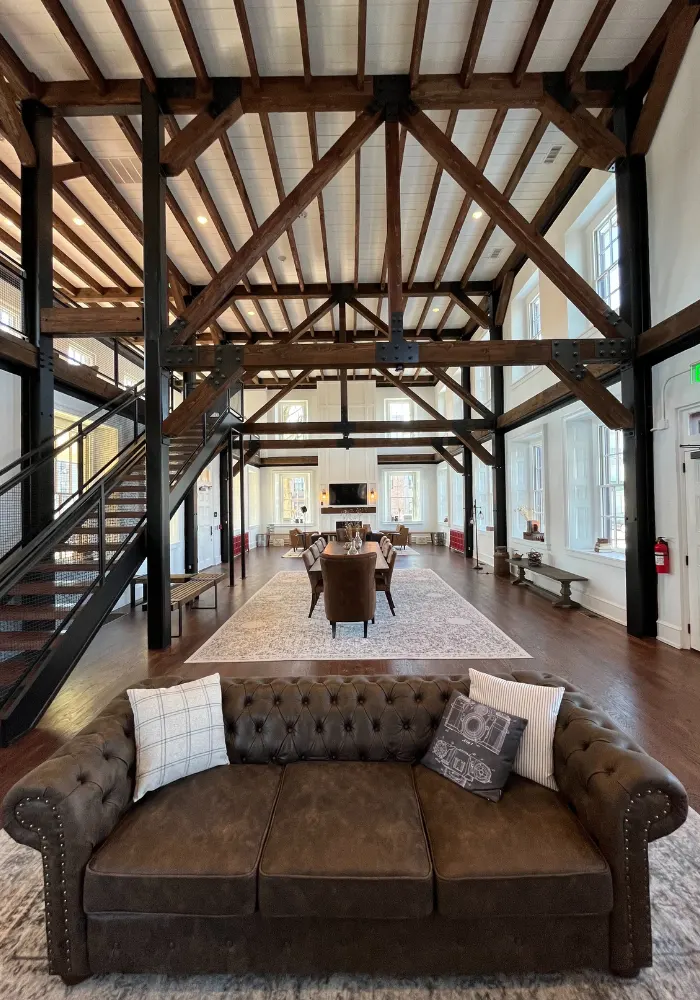 The interior of a beautiful new Barndominium with high ceilings, wood beams, and decorative concrete floors stamped to resemble hard wood 